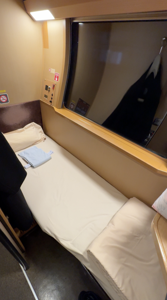 Bed, pillow and folded yukata beside the window in our Sunrise Express Single room