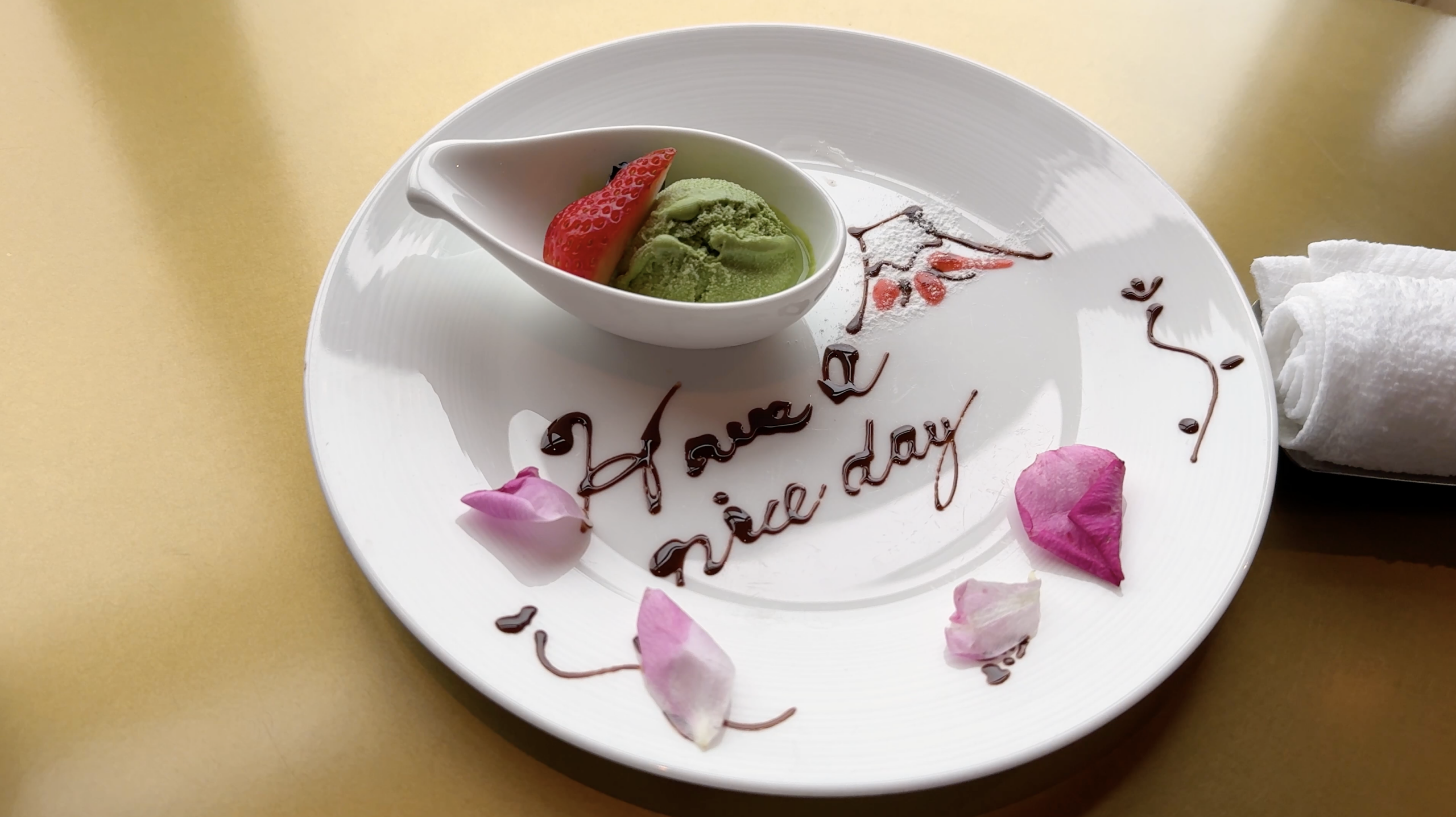 Green ice cream and a strawberry on a plate decorated with Have a nice day at Mandarin Oriental Tokyo