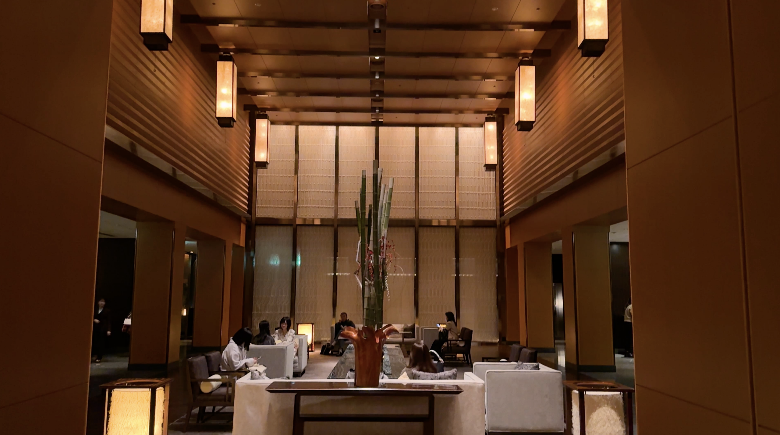 Warm wooden lobby with hanging lanterns and a tall floral display at Mandarin Oriental Tokyo