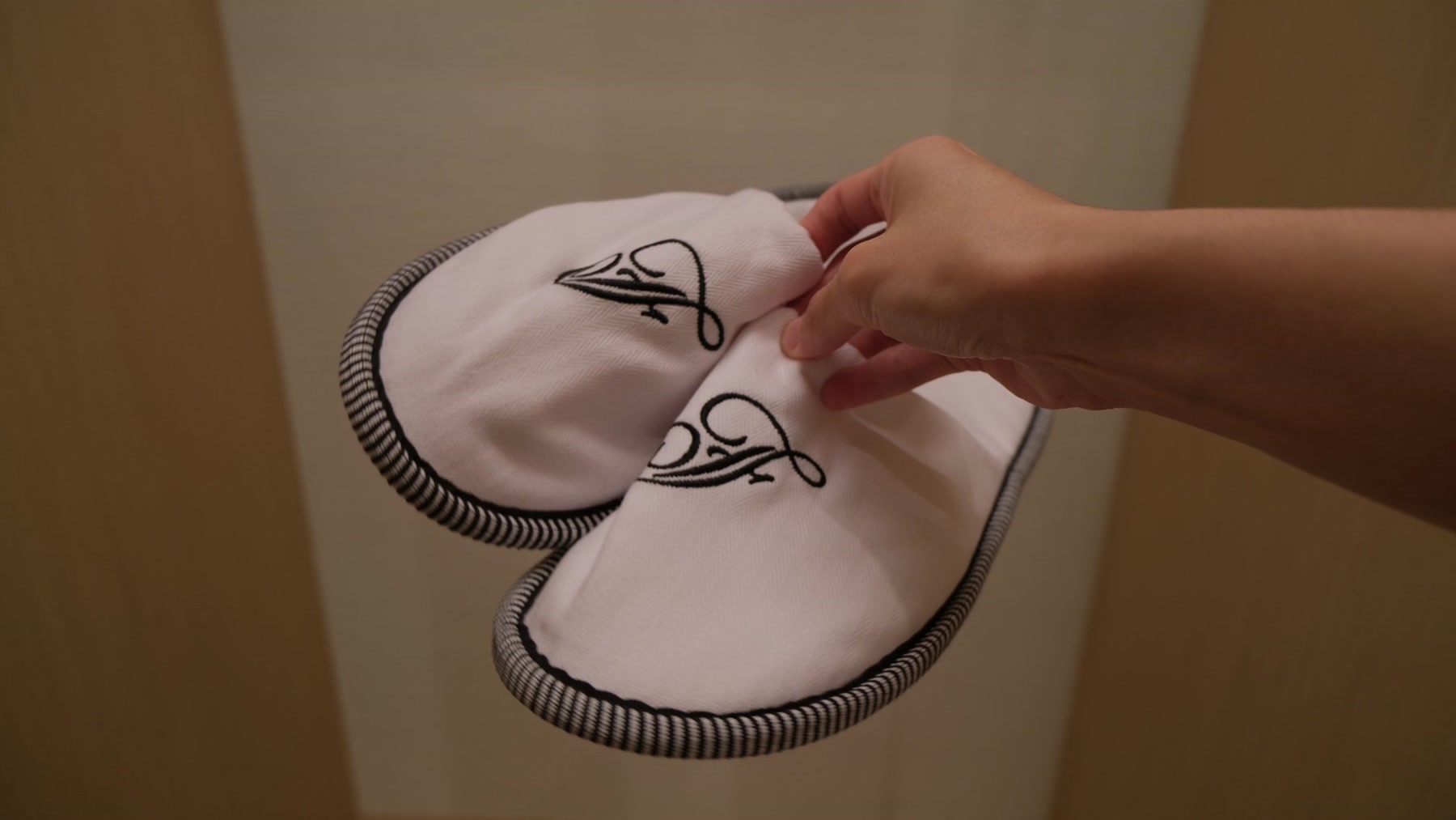 White Fairmont slippers with embroidered monograms and dark piping