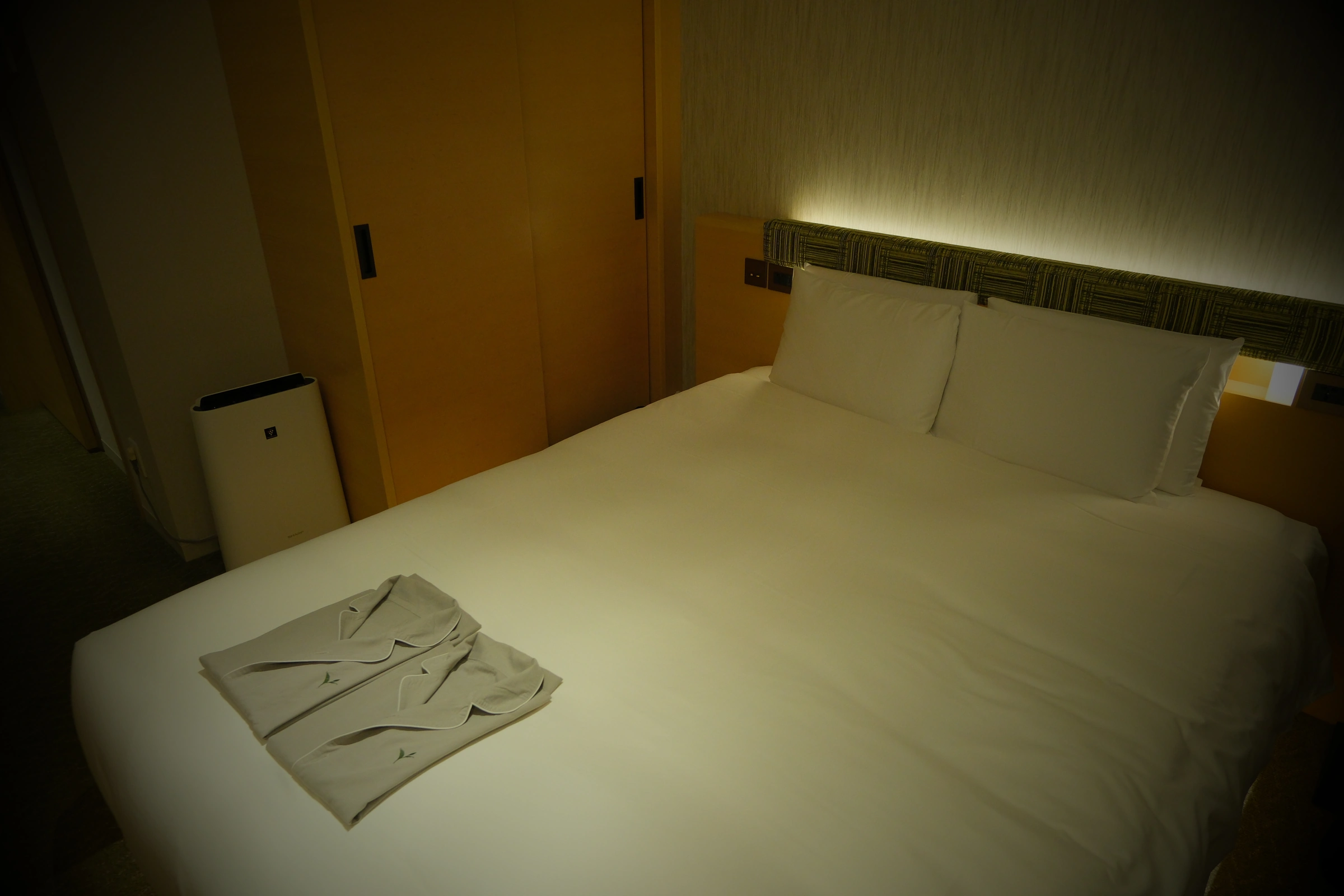 Double bed, green headboard and folded tea-leaf-embroidered nightwear