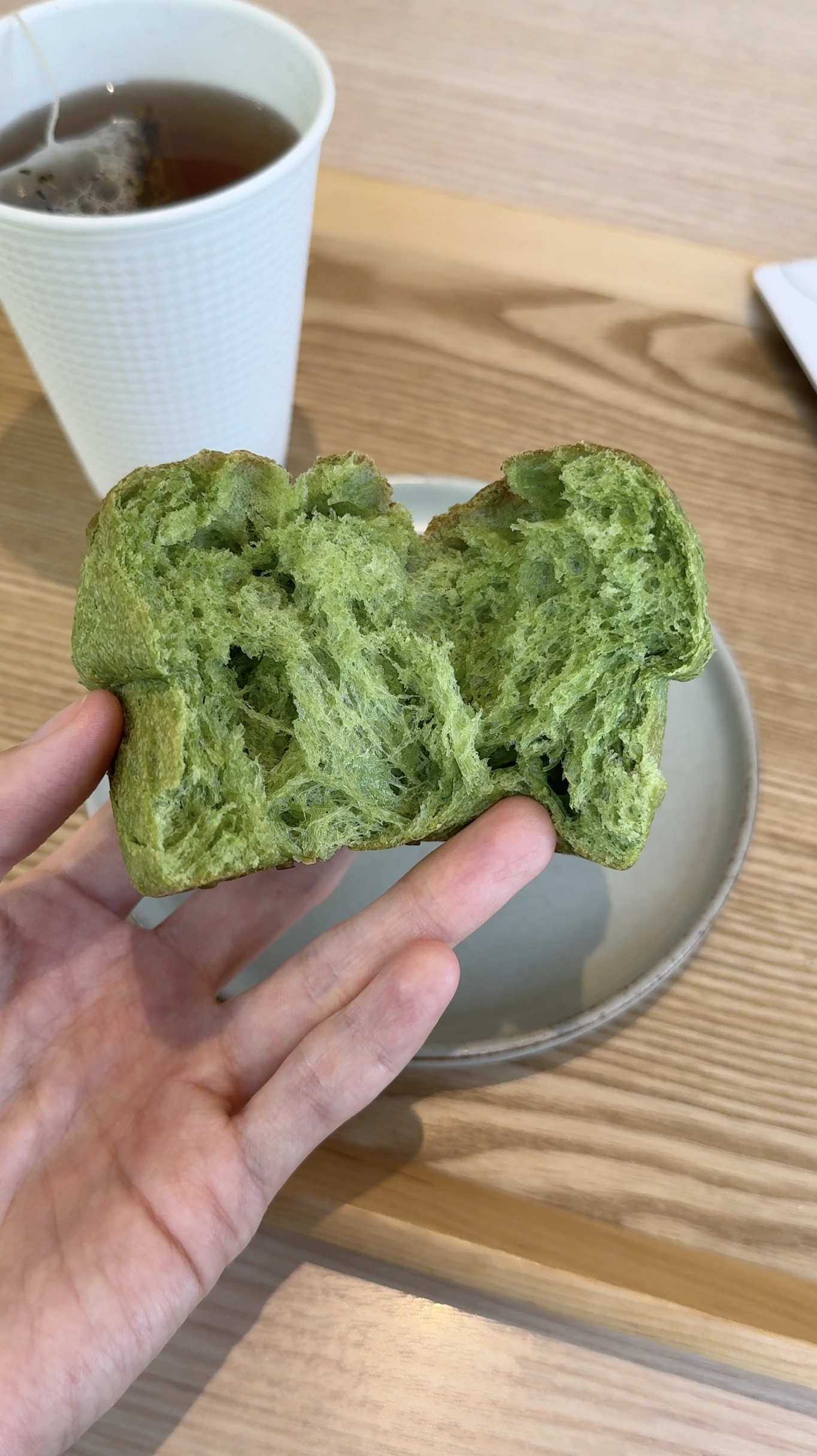 A piece of green bread pulled open beside a cup of tea at Hotel 1899 Tokyo