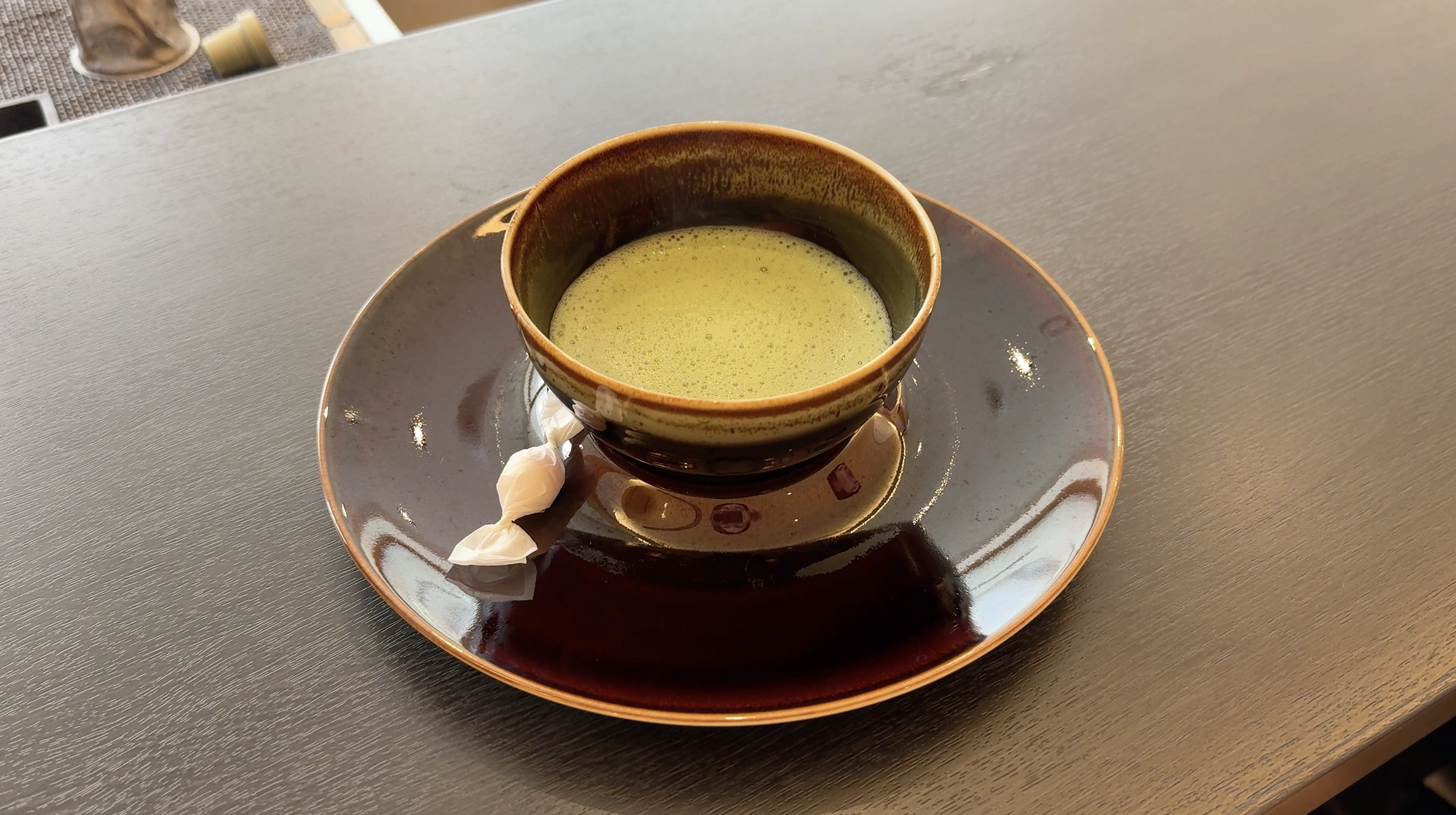 A bowl of frothy matcha with a wrapped sweet at Hotel 1899 Tokyo