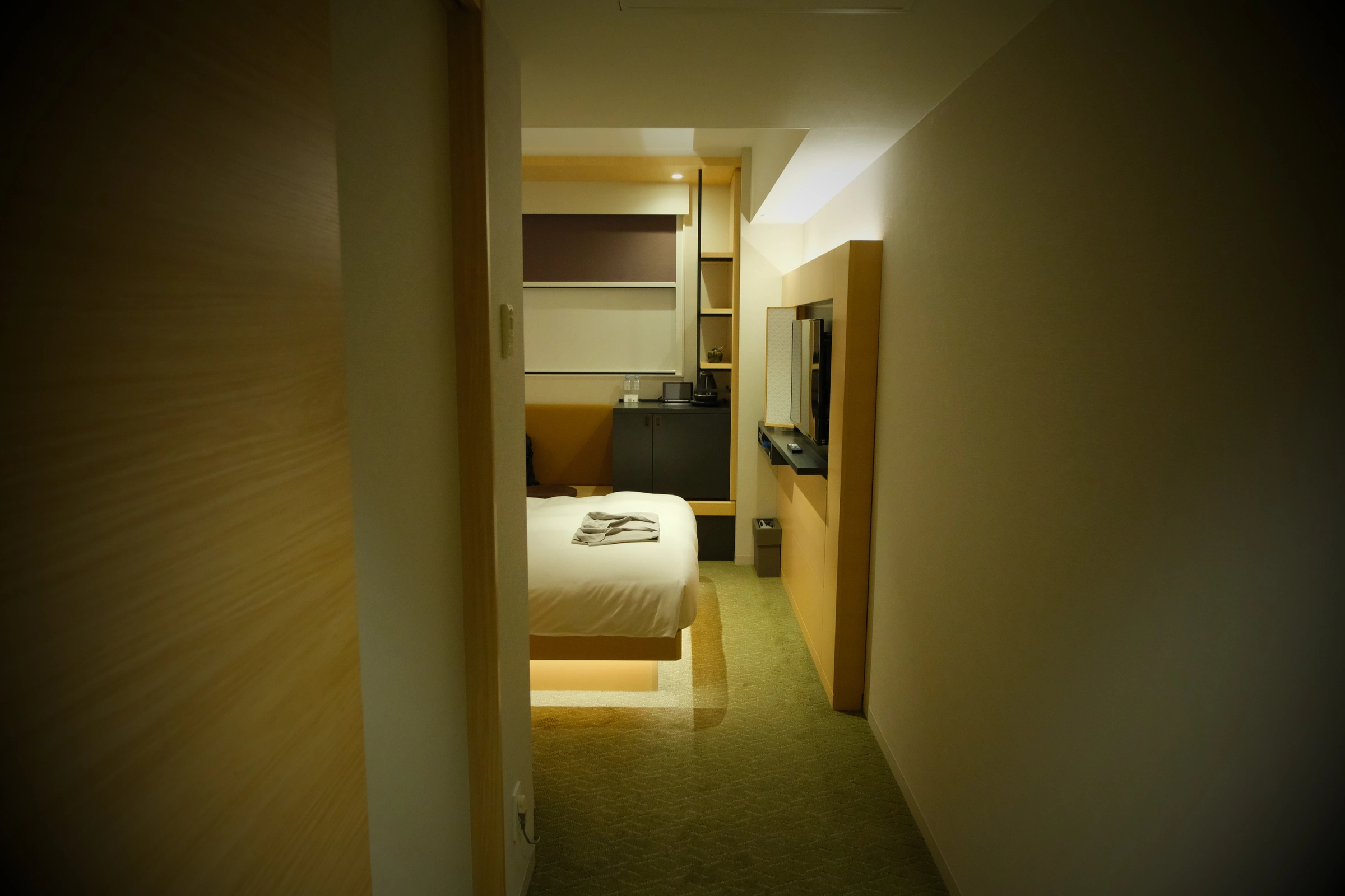 View from the room entrance toward the bed, shelving, tea station and television