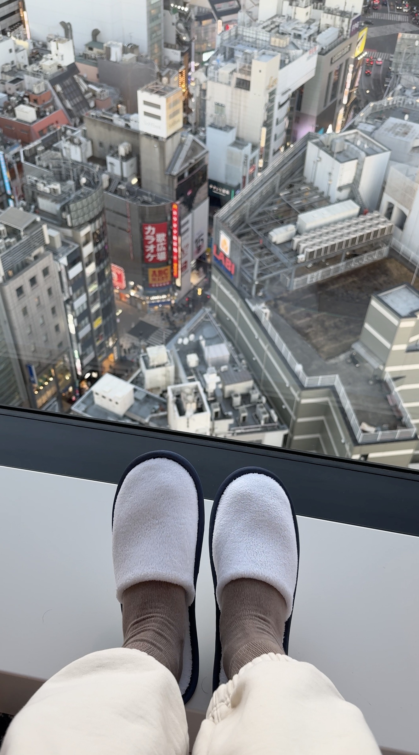 Hotel slippers beside the window overlooking Shibuya streets and the crossing