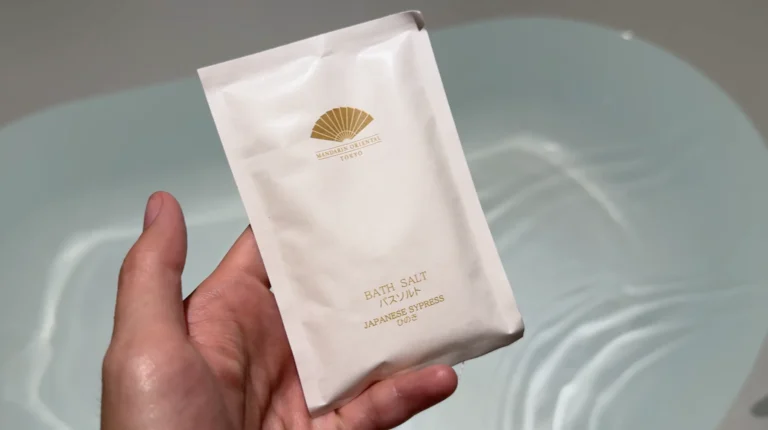 Mandarin Oriental Tokyo Japanese cypress bath-salt packet held above a filled bathtub