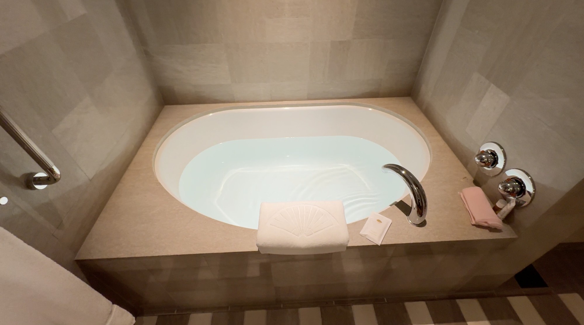 Bathtub prepared with water and a folded Mandarin Oriental towel in our room