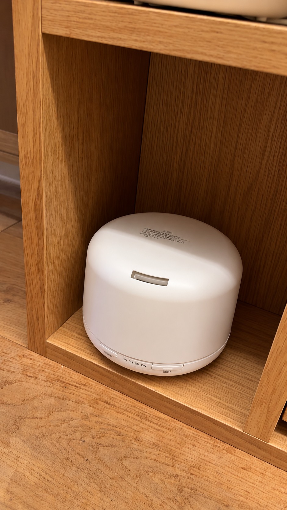 White MUJI aroma diffuser on a wooden shelf in our hotel room