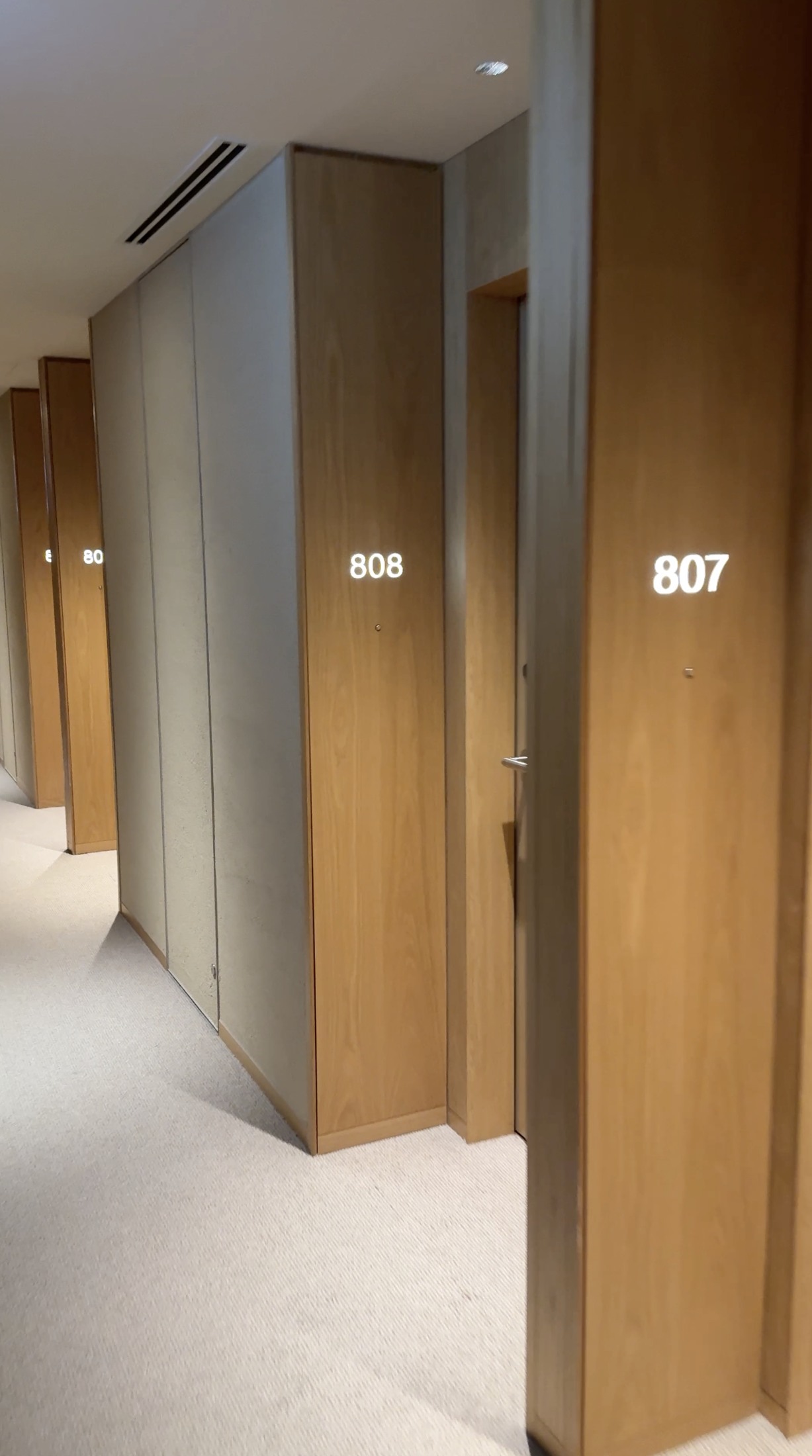 Wooden doors and illuminated room numbers on MUJI HOTEL GINZA’s eighth floor