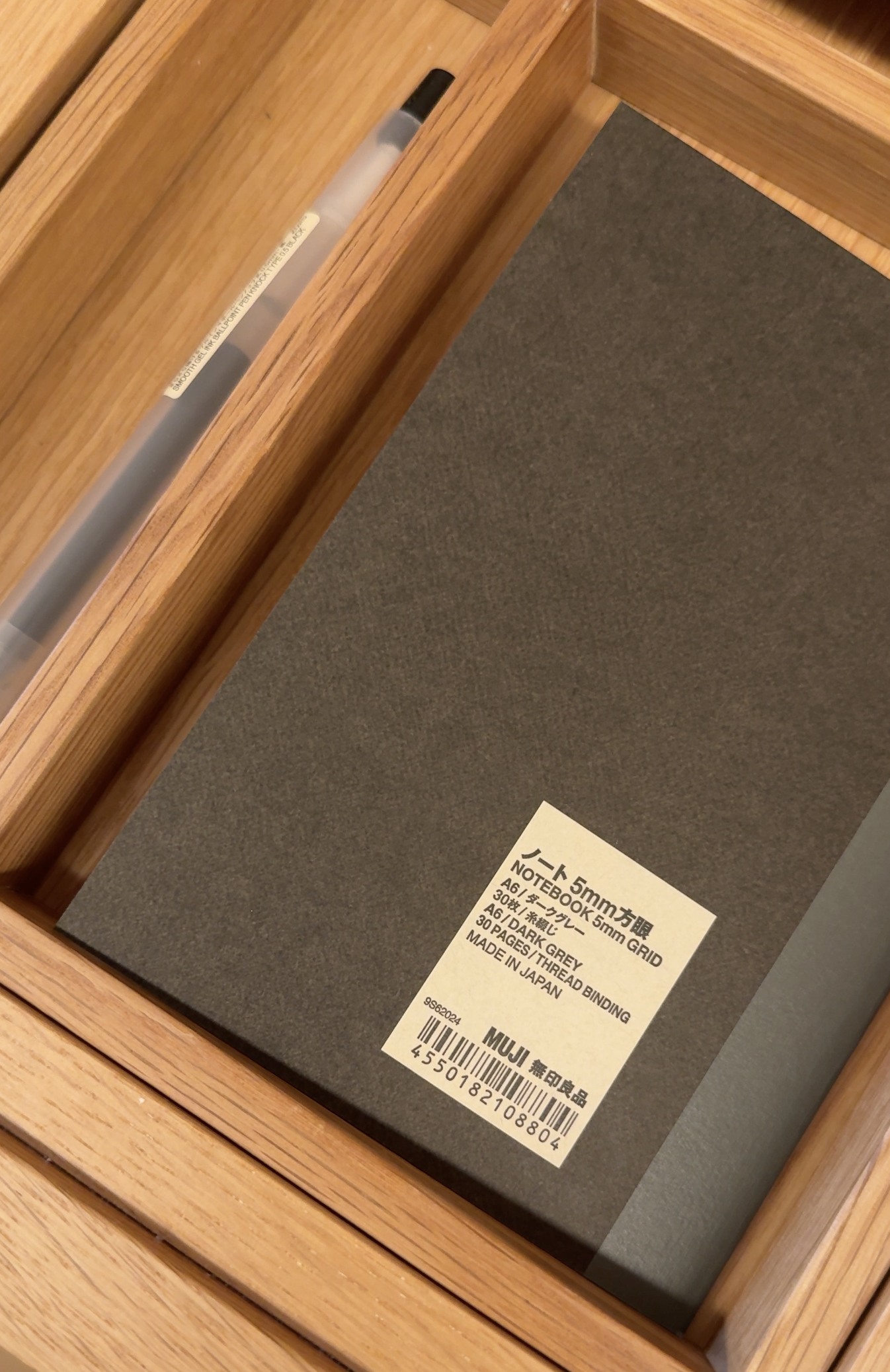 MUJI A6 dark gray grid notebook and smooth gel ink pen provided in the room